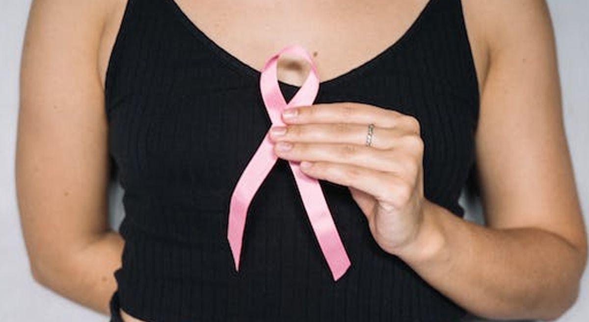 Picture of a person holding a breast cancer awareness ribbon.